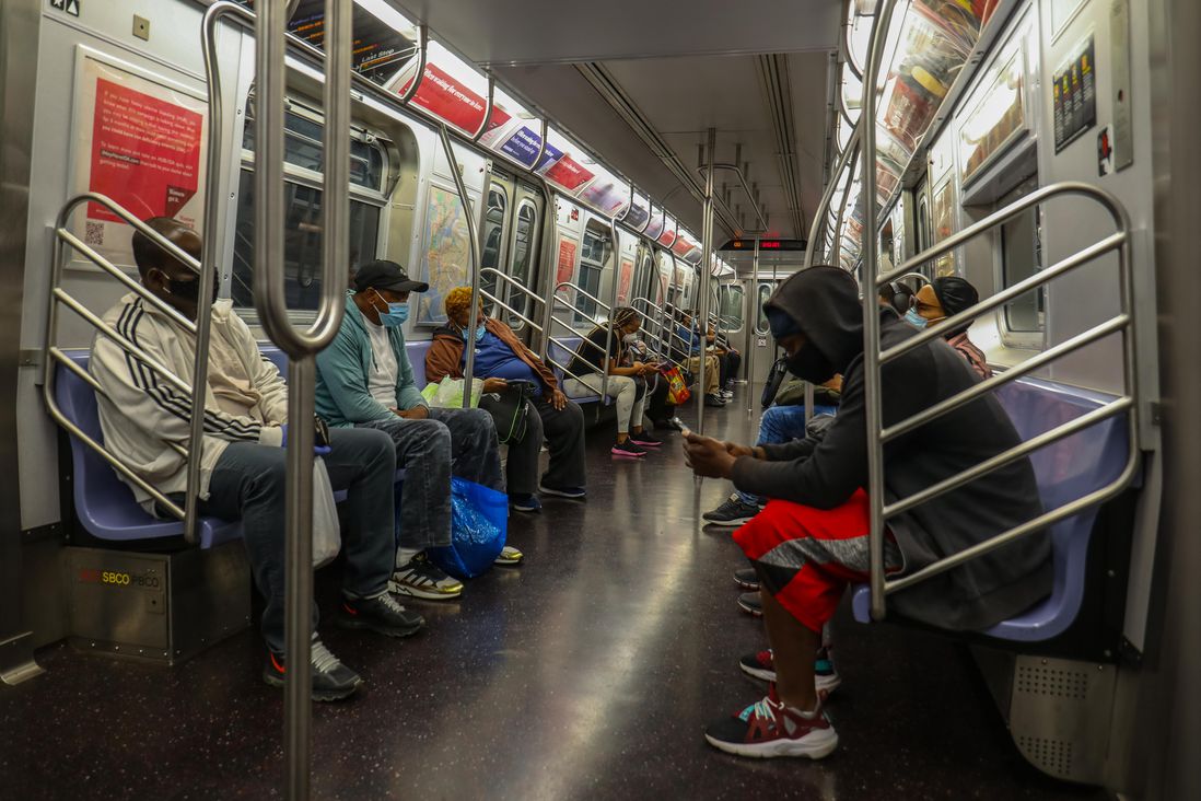 A subway car with a fair amount of people sitting on the benches
